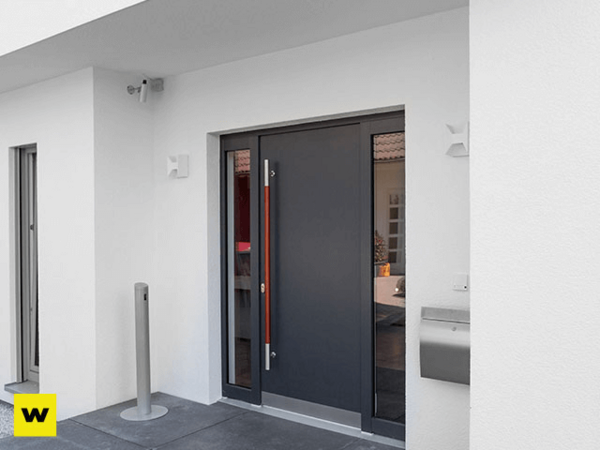 Moderne Haustür aus Aluminium mit seitlichem Briefkasten an weißer Hausfassade.